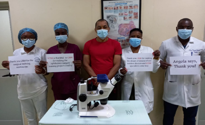 Médecins avec microscope et pancartes disant "merci CBM Luxembourg"